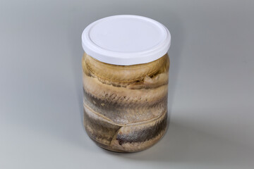 Pickled herring fillets in sealed jar on gray background - 787046103
