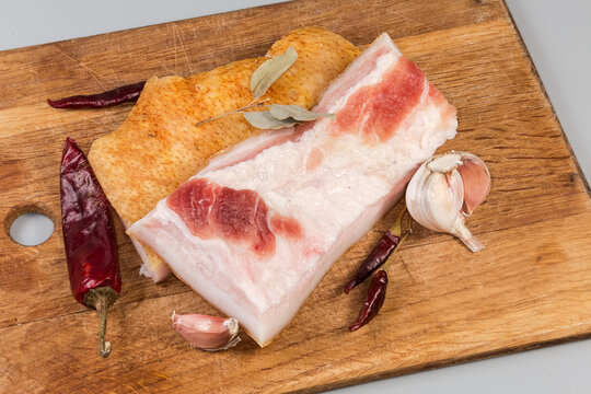 Salted pork fatback pieces among different spices on cutting board