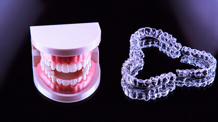 Invisible and removable aligner trays for teeth straightening with artificial jaw lie on a black background