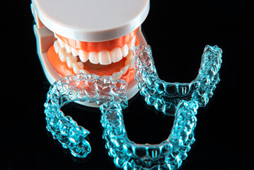 Invisible and removable aligner trays for teeth straightening with artificial jaw lie on a black...