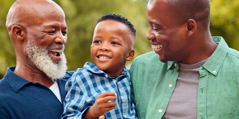 Three Generation Male Family Laughing Hugging Grandson Standing Outdoors In Countryside - obrazy, fototapety, plakaty