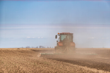 Farmer works the land, plowing a field with a modern red tractor on a sunny day