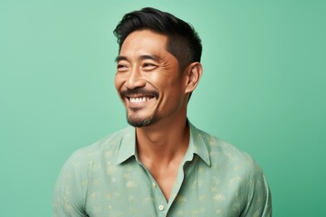 Obraz premium Portrait of a blissful asian man in his 40s donning a trendy cropped top isolated in pastel green background