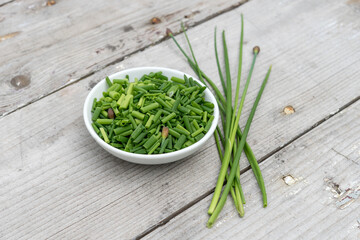 Fototapeta na wymiar White bowl with sliced ​​chives on a light wooden background