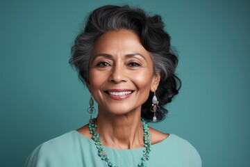 Portrait of a smiling indian woman in her 60s donning a classic fedora in pastel teal background - obrazy, fototapety, plakaty