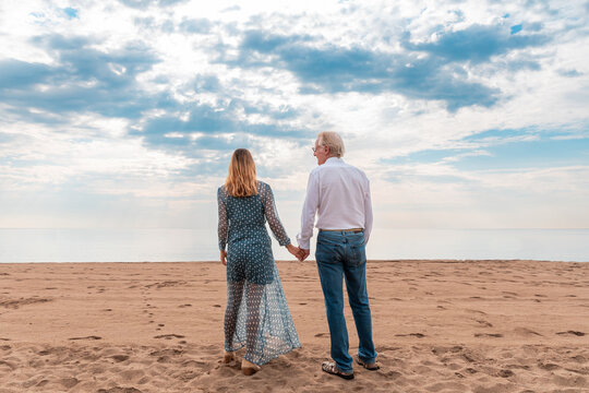 Mature couple holding hands on beach at sunset