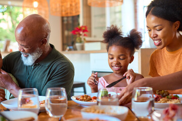 Multi-Generation Family Around Table Serving And Eating Meal At Home Together