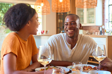 Smiling Couple Enjoying Meal With Wine At Home Together