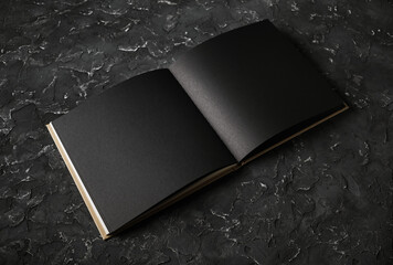 Blank black booklet on black plaster background. Responsive design template.