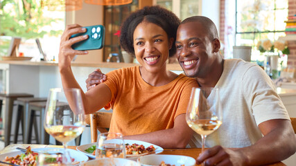 Smiling Couple Enjoying Meal With Wine At Home Together Posing For Selfie On Phone