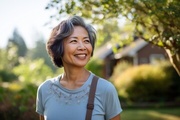 Portrait of a satisfied asian woman in her 60s dressed in a casual t-shirt in soft blue background