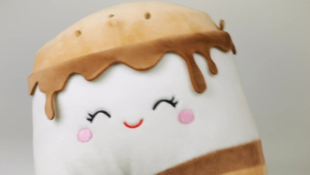 Stuffed and fluffy toy pillow playing and dancing on a white background.