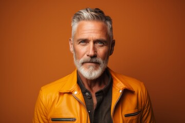 Obraz premium Portrait of a merry man in his 50s wearing a trendy bomber jacket in front of soft orange background