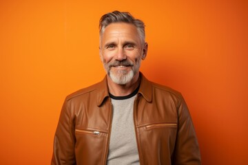 Obraz premium Portrait of a merry man in his 50s wearing a trendy bomber jacket over soft orange background