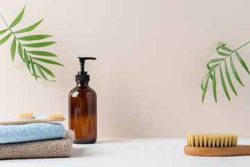 Stack of terry towels, brown recycled glass bottle with soap dispenser on white background. Caddy tray with cosmetics products over bath. Skin care and morning routine concepts