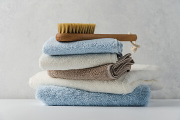 Stack of nude cotton towels with massage brush on white background