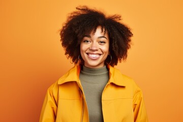 Obraz na płótnie Canvas Portrait of a glad afro-american woman in her 20s dressed in a water-resistant gilet on soft orange background