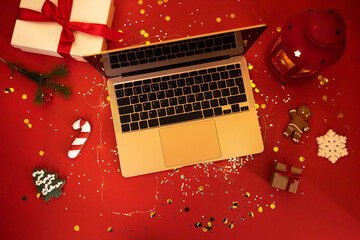 The open laptop lies on a red festive table with glitters and confetti. - Powered by Adobe