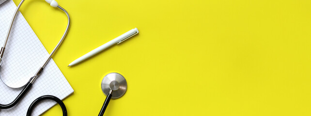 Stethoscope, notepad and pen on a yellow background, top view. Cardiology and healthcare concept....