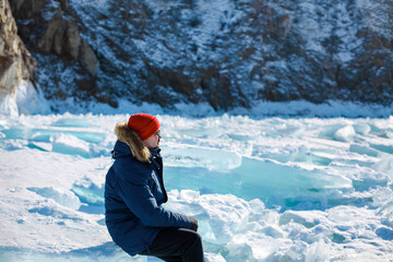 Portrait of the man tourist in red cap and blue jacket wearing sunglasses on ice