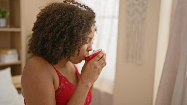 African american woman drinking coffee in bedroom