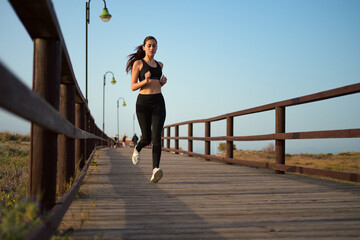 Young woman jogging on a wooden boardwalk at dusk