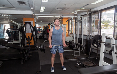 Man lifting weights in a gym. The gym is well-equipped, with various exercise machines visible....