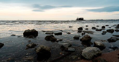 Low light with shadow of rocks. There are ruins of building in the sea. During the evening time.
