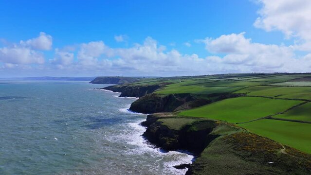 Aerial shot tracking out and away from West Wales coastline on windy but sunny day
