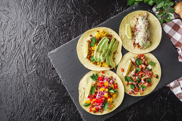 set of delicious fresh colorful tacos on a dark background