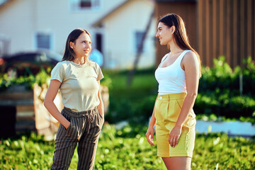 Street conversation between two European women in their 20s on summer day in countryside.