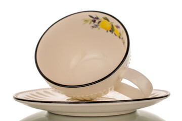 One porcelain cup with saucer, macro, isolated on white background.