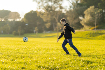 A boy kicks a soccer ball in a field