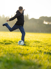 A boy kicks a soccer ball in a field