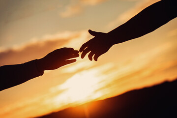 The hands of a couple in the sunset. Silhouette of helping hand concept. Handshake silhouette, sunset hands together, teamwork. Outstretched hands, salvation, help silhouette, concept help
