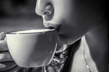 Girl drinking coffee. Woman holding cup hot coffees in hands. Black and white