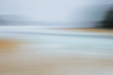 Intentional camera movement (ICM) image of seashore with reeds and ground covered with snow in winter created by motion blur.