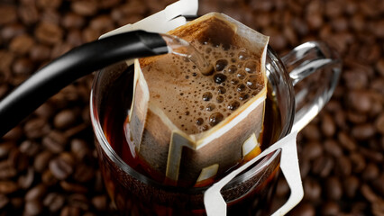 Pouring hot water in glass with drip coffee bag 