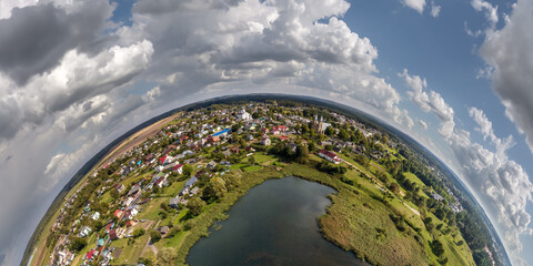 Aerial view from high altitude tiny planet in sky with clouds overlooking old town, urban development, buildings and crossroads. Transformation of spherical 360 panorama in abstract aerial view.