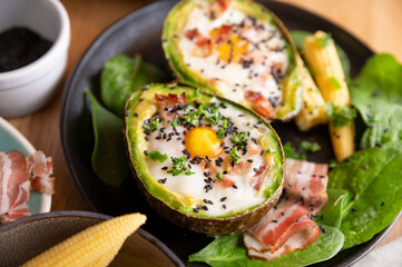 Cooking Avocado with Egg and Bacon. The girl prepares a healthy meal, close-up of her hands and products in the frame. Breakfast for complete nutrition