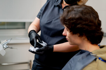 dental office blonde dentist in a black uniform consulting patient showing a dental cast