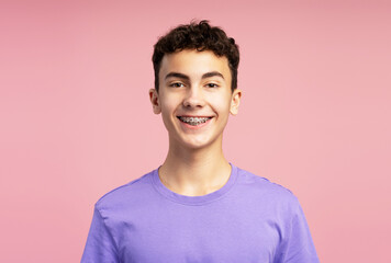 Happy smiling boy with dental braces wearing purple t shirt looking at camera