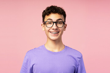 Portrait of smiling happy boy, teenager with braces wearing eyeglasses looking at camera