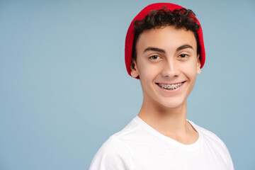 Happy attractive boy teenager with braces wearing red hat looking at camera