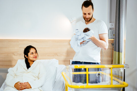 Adult Caucasian man holding a newborn baby in hospital