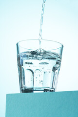 Pouring of water in glass on blue. - 787136901