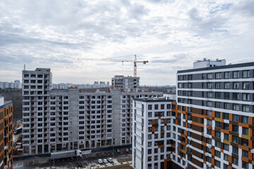 Fototapeta na wymiar A crane and a building under construction against a blue sky background. Builders work on large construction sites, Building a house is not necessary for new high-rise buildings