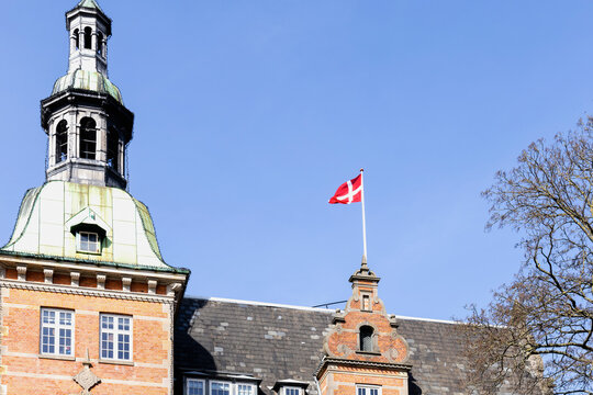 Danish flag on the roof of a building against a blue sky.