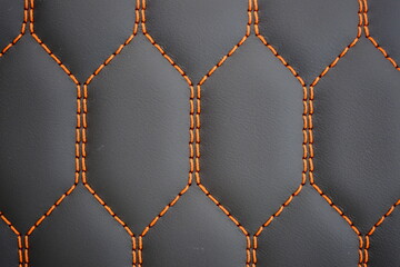 Orange contrast thread on natural black leather car seat close-up