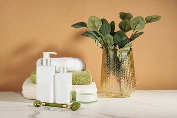 Skin care products in the bathroom. Face cream, serum bottle, jade roller and stack of towels. - 787143571